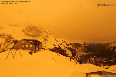 Beispiel einer Orangefärbung des Himmels durch Saharastaub bei einem Saharastaubausbruch am 15.03.2022 bei der Glecksteinhütte bei Grindelwald im Kanton Bern (Quelle Foto-Webcam)