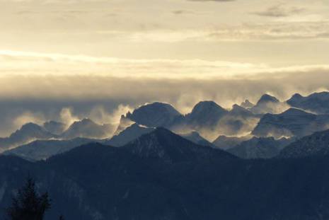 Schneefahnen über den Alpengipfel bei Südweststurm, von der Morgensonnen beschienen.