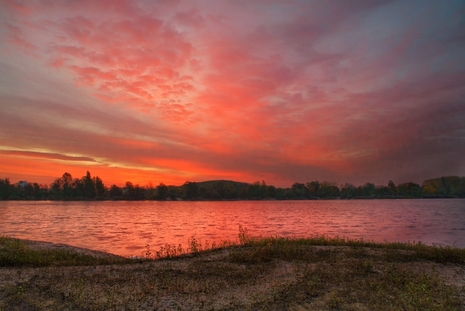 Morgenrot: Rotbeleuchtete Wolken spiegeln sich auf einen See. (Quelle Ingo Bertram)