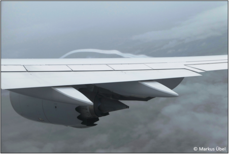 Durch Kondensation sichtbar gemachte gekrümmte Strömung oberhalb der Tragfläche eines Flugzeugs